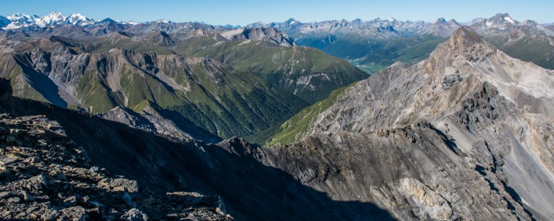 Blick vom Piz Quattervals nach Süden. Rechts der Piz d’Esan, in der Mitte die Val Trupchun und hinten die Dörfer Madulain und La Punt im Oberengadin.
