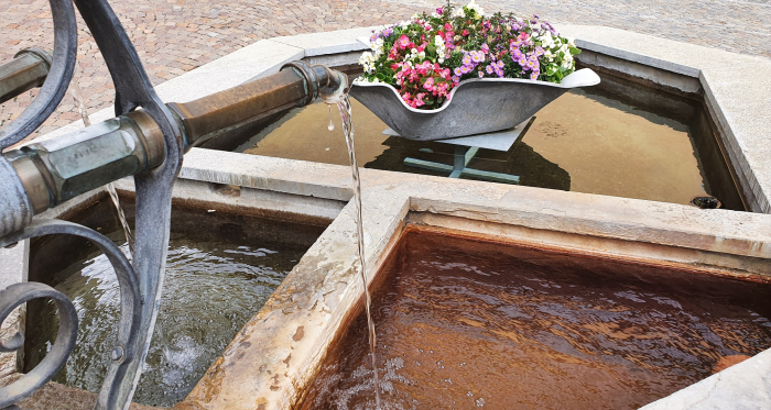 Mineralwasser der Sotsass-Quelle am Dorfbrunnen Bagnera