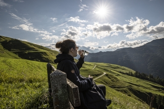 Madlaina Janett auf einem Bänkli mit Ausblick auf die Engadiner Bergwelt.