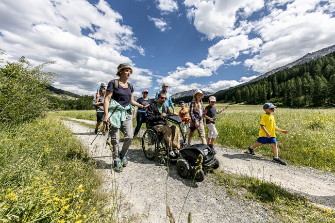 Familie mit Rollstuhlfahrer spaziert im Val Müstair