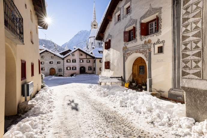Dorf Scuol im Winter mit verschneiter Gasse und Engadiner Häusern im Unterengadin, Graubünden, Schweiz