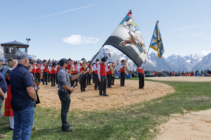 Fahnenschwinger zeigt sein Können am Schwingfest in Scuol vor alpiner Kulisse.