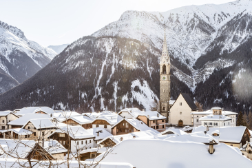 Winter in Sent, Sur En im Engadin – traditionelles Bergdorf mit Kirche, Schnee und beeindruckender Bergkulisse in Graubünden