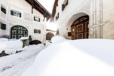 Dorf Guarda im Winter mit verschneiten Engadiner Häusern und historischem Torbogen in Graubünden, Schweiz
